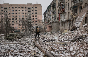 Ukrainian serviceman walks near apartment buildings damaged by a Russian military strike