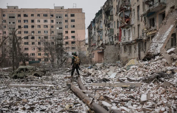 Ukrainian serviceman walks near apartment buildings damaged by a Russian military strike