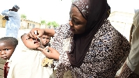 A health official tries to immunize a child during a vaccination campaign in Kano