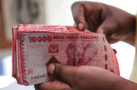An individual is seen holding Tanzanian currency