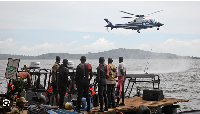 Ugandan divers look up as a helicopter searches for victims of a boat which capsized in 2018