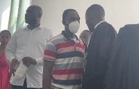 The accused (with a nose mask), speaking to a lawyer in court