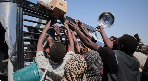 Sudanese families reach out as aid workers distribute food supplies at a camp in al-Dabba