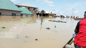 An official of the Nigerian Red Cross Society canoes through a submerged market in Lokoja