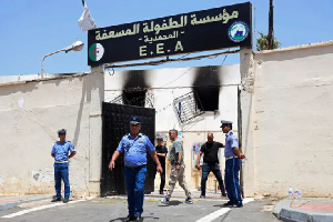 Policemen stand outside the fire damaged orphanage in Mohammedia, near Algiers