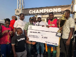 The winners receiving a dummy cheque from Stephen Appiah