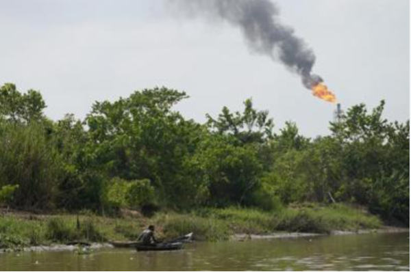 A man paddle his canoe past a gas flare in the Niger Delta near the village of Ogboinbiri, Nigeria