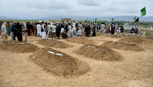 Afghan relatives offer prayers during a burial ceremony for victims of flooding in Baghlan province