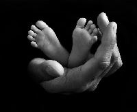 A baby's legs in the hands of a parent