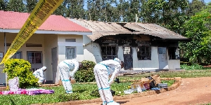 Forensic police officers in front of a burnt dormitory at Salama School for the Blind in Luga,Mukono