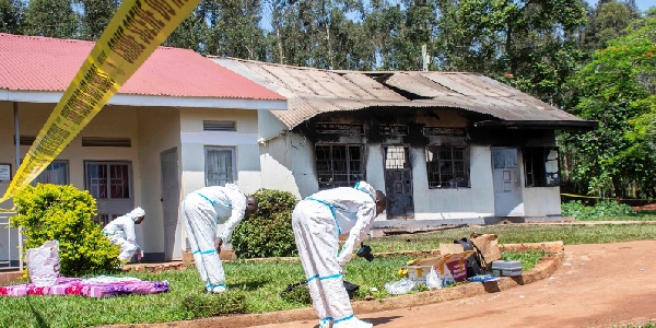 Forensic police officers in front of a burnt dormitory at Salama School for the Blind in Luga,Mukono