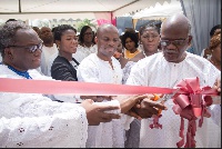 Prof. Aheto (right) being assisted by others to cut the tape at the official launch