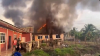 An image of the intense orange flames engulfing the roof of a light-colored building