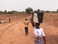 A resident after hours of collecting water at a dried up dam in Tamale