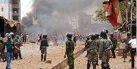 File photo: Guinea security forces, center, face people rioting and burning rubbish and other goods