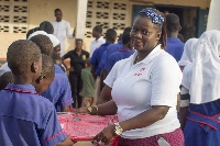 Maame Dufie Cudjoe, CSR Manager hands over a bag to one of the students