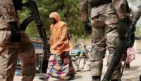 A woman walks past Nigerian soldiers at a checkpoint in Gwoza, northeast, Nigeria