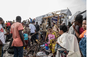 People gather at the site of explosions at a camp for displaced people [Moses Sawasawa/AP]