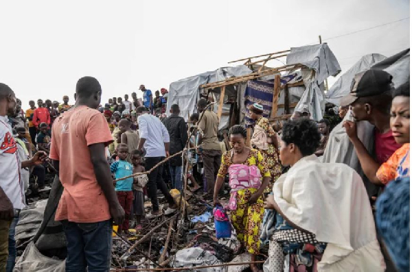 People gather at the site of explosions at a camp for displaced people [Moses Sawasawa/AP]
