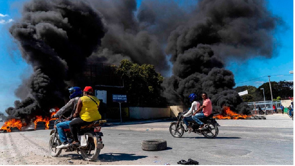 Motorcyclists drive by burning tires during a police demonstration after a gang attack on a police
