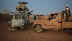 A Malian soldier stands on a pick-up truck next to a damaged helicopter A Malian soldier stands on a pick-up truck next to a damaged helicopter