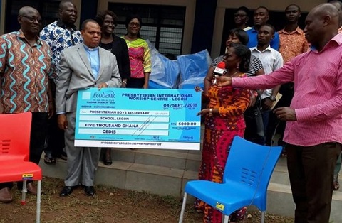 Rev. Erasmus Mensah Laryea presenting the cheque and the chairs to the headmistress of the school