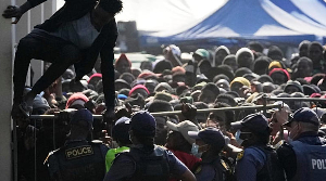 A Malawian migrant climbs over a barricade at a temporary detention center in Durban, South Africa