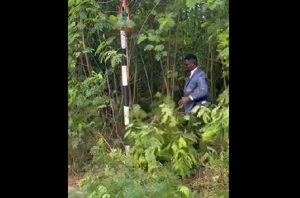 Nana Tea got down in his suit and started weeding the edge of the GIMPA Road