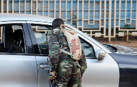 A soldier checks a vehicle at a checkpoint following a mutineers' attack on airport and presidency