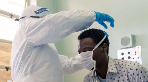 A medical staff member places a face mask on a mock patient