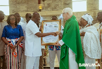 Dr Bawumia (in white) receives citation from Rev Fr Campbell (in green liturgical vestment)