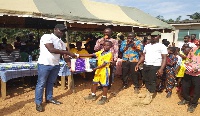 Hon. Charles Kwesi giving out learning materials to a pupil of the school