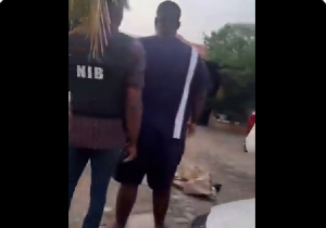 Some officials and Alfred Kumi (in blue T-Shirt and shorts) at his residence during his arrest