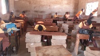 Pupils in Tono Junior High School sit on stacks of blocks to learn
