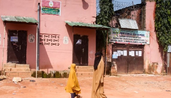 Young girls walk past a boarding school in Kaduna where hundreds of students were rescued in 2019