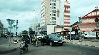 Cars and motorbikes ride on a road in Cotonou, Benin