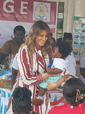 US First Lady, Melania Trump carrying a child during her donation in Accra