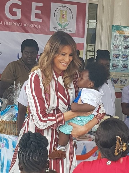 US First Lady, Melania Trump carrying a child during her donation in Accra