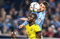 Defender Jonathan Mensah challenges David Villa to the ball in a match