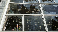 A worker removes shards of glass from a broken window, at a school damaged by a Russian missile