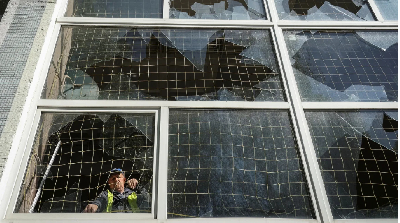 A worker removes shards of glass from a broken window, at a school damaged by a Russian missile