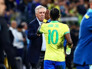 Carlo Ancelotti (in black suit) congratulating Vinicius Jr (in yellow jersey) after the game