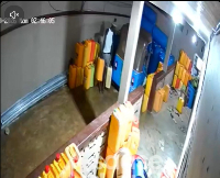 The suspect wearing a white singlet and carrying two gallons