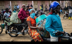 People wait at the entrance to the central market while sanitation workers disinfect the area