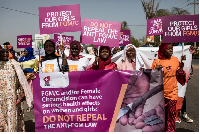 Anti-FGM protesters hold placards outside the National Assembly in Banju