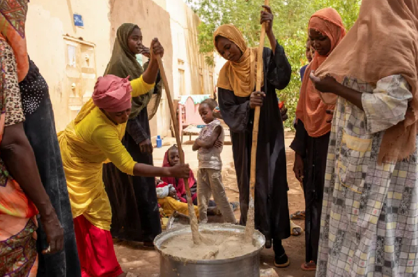 Sudanese women from community kitchens run by local volunteers prepare meals for people