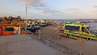 Rescuers and ambulance cars wait on the beach for possible survivors