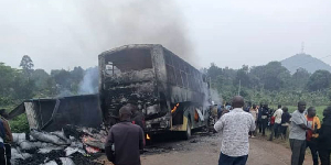 First responders and survivors stand near the burning wreckage of the bus and truck, which collided