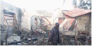 A policeman walks through burnt beds and metallic boxes at Victory Nursery and Primary School