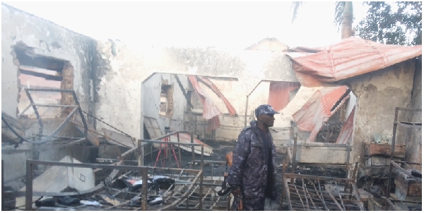 A policeman walks through burnt beds and metallic boxes at Victory Nursery and Primary School